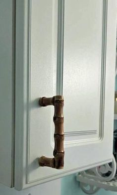 a close up of a kitchen cabinet door handle on a white cupboard with blue walls in the background