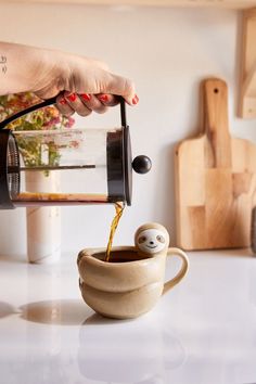 a person pours coffee into a cup with a slot face on the side,