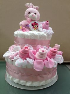 a pink and white diaper cake with a teddy bear sitting on top of it