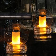 three lit candles floating in water at night