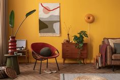 a living room with yellow walls and wooden flooring, two chairs, a rug on the floor and a painting on the wall