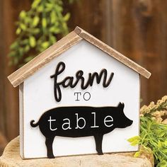 a farm to table sign sitting on top of a wooden stump next to a potted plant