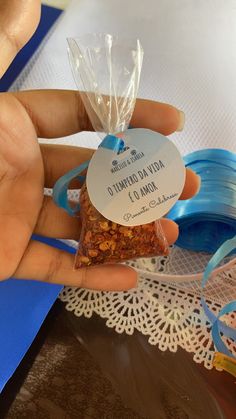 a person holding a bag of granola next to a blue ribbon on top of a table