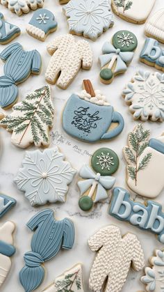 cookies decorated with blue and white frosting are on a counter top, surrounded by snowflakes