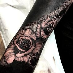 a woman's arm with black and white tattoos on it, featuring flowers in the center