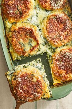 spinach lasagna casserole in a green dish with a wooden spoon