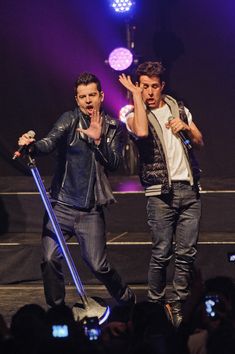 two men standing on stage with their hands in the air