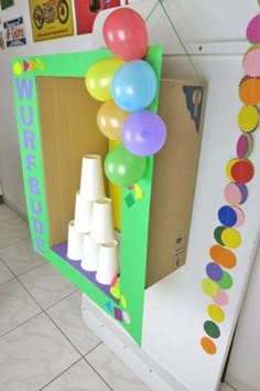 an open cardboard box with balloons and streamers hanging from the ceiling in front of it