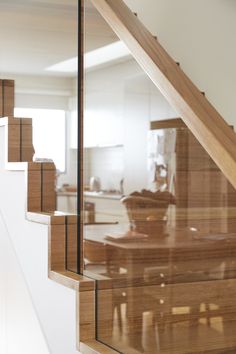 a wooden table sitting under a stair case next to a glass wall in a kitchen