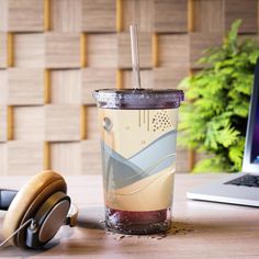 a cup with headphones next to a laptop