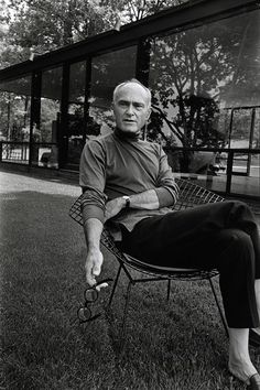 an older man sitting on top of a chair in the grass next to a building