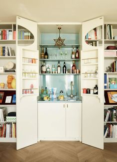 a kitchen with white cabinets and shelves filled with bottles, books, and other items