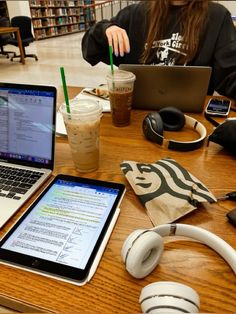 a person sitting at a table with two laptops and headphones in front of them