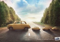 an old yellow car driving down a road next to two small cars on the side