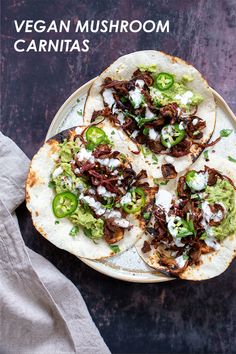 three tacos on a plate with sour cream and jalapeno peppers in the middle