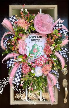 a pink and black wreath with flowers on the front door, saying don't ask