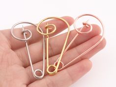 three different types of hair pins in the palm of someone's hand on a white background