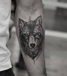 a black and white photo of a wolf tattoo on the left arm with an arrow in it's center