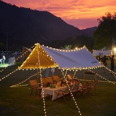 a large tent with lights on it in the middle of a field