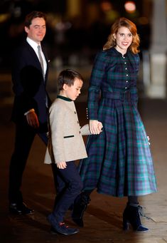 a woman in a blue dress and a boy in a black suit are walking down the street