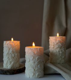 three white candles sitting on top of a table