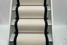 a set of stairs with black and white carpet on the bottom, along with two rolls of toilet paper