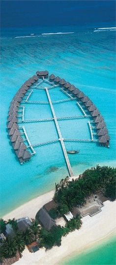 an aerial view of a resort in the middle of the ocean with water and palm trees