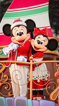 two mickey and minnie mouse characters standing next to each other on a disney world float