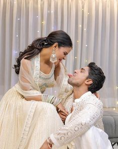 a man kneeling down next to a woman in a white dress