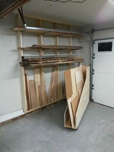 a garage filled with lots of wooden planks next to a white door and storage area