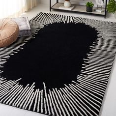 a black and white rug on the floor in a living room with a round pillow