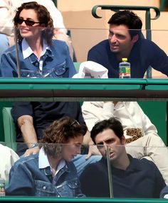 two men sitting next to each other at a tennis match