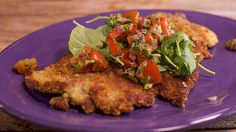 a purple plate topped with fried chicken and veggies on top of a wooden table