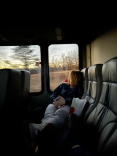 two people sitting in the back seat of a vehicle looking out the window at an open field