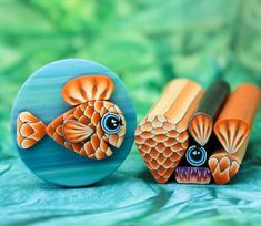 two orange and blue fish shaped erasers sitting next to each other on a green surface