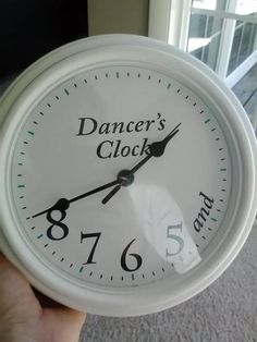 a white clock with the words dancer's clock on it in front of a window