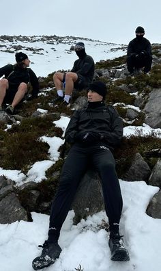 three people sitting on rocks in the snow