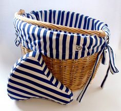 a basket with blue and white striped fabric on it, sitting next to a pillow