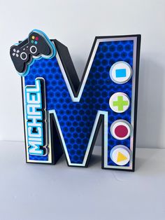 the letter m is made up of video game controllers and letters that spell it out