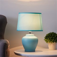 a blue lamp sitting on top of a table next to a potted green plant