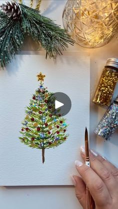 someone is painting a christmas tree on a piece of paper with watercolor pencils