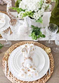 the table is set with white and gold plates, napkins, silverware, and flowers