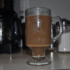 there is a glass mug with liquid in it on the counter top next to coffee maker