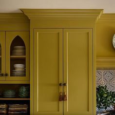 a kitchen with yellow cabinets and plates on the counter