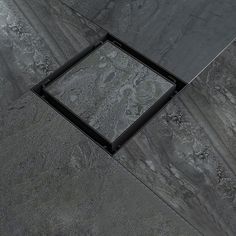 a tile floor with a black square in the middle and a gray marble pattern on it