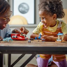 a woman and child playing with toys at a table