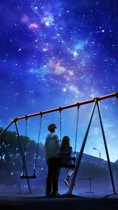 two people standing on a swing in front of a night sky