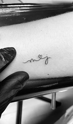 a person's arm with the word love on it and a small heart in cursive writing