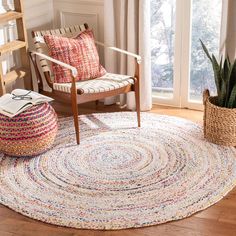 a living room with a chair, rug and potted plant on the hardwood floor