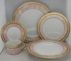 a pink and gold dinner set with matching plates